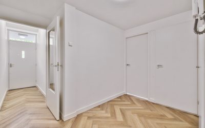 an empty interior area with white walls and laminate flooring